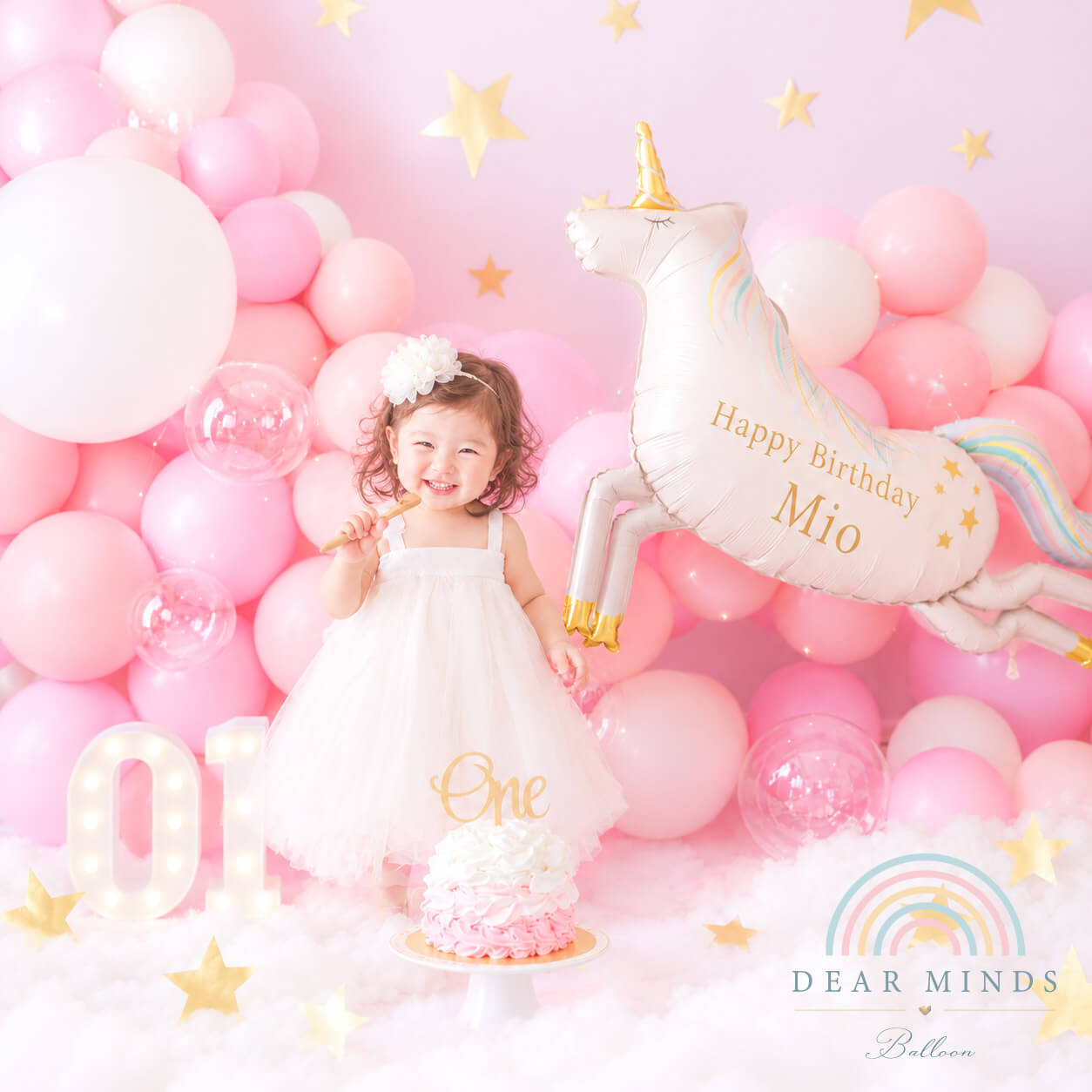 1歳の誕生日を彩るピンクのバルーン装飾とユニコーンバルーン、笑顔の女の子